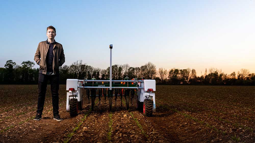 Ein Entwickler neben seinem autonomen Roboter zum Jäten von Feldern