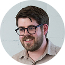 re-morrow-76 2 Portrait of a smiling man with dark hair, beard, and glasses in a circular portrait frame.